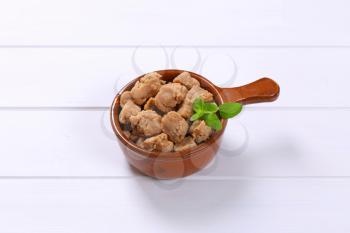 saucepan of soy meat cubes on white wooden background