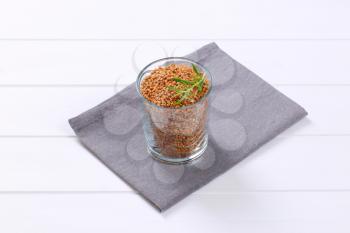 glass of raw buckwheat on grey place mat