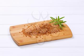 pile of raw buckwheat on wooden cutting board
