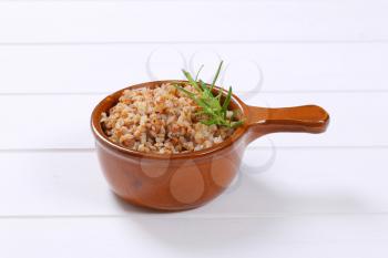 saucepan of cooked buckwheat on white wooden background