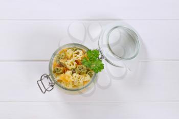 jar of cooked colored pasta on white wooden background