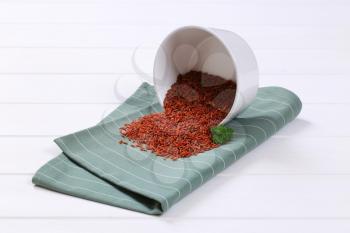 bowl of red rice spilt out on grey place mat