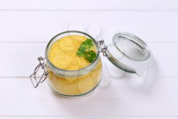 jar of raw millet on white wooden background
