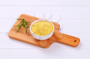 bowl of raw millet on wooden cutting board