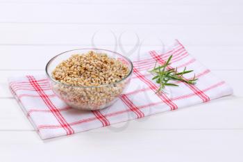 bowl of cooked pearl barley on checkered dishtowel