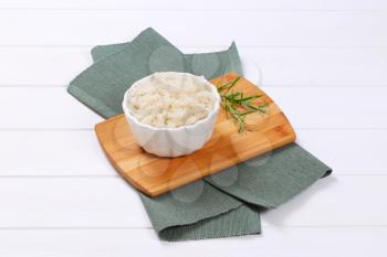 bowl of cooked rice pasta fusilli on wooden cutting board
