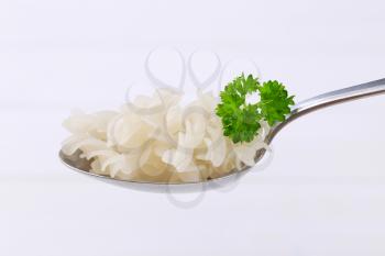 spoon of cooked rice pasta fusilli on white wooden background