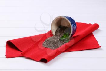 bowl of chia seeds spilt out on red place mat