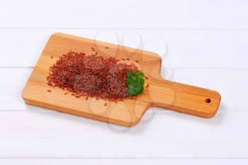 pile of red rice on wooden cutting board