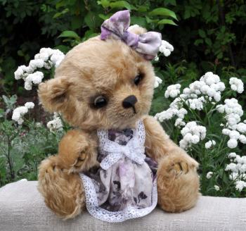 Handmade, the sewed toy: teddy-bear Lucky on a on an ancient linen cloth among flowers