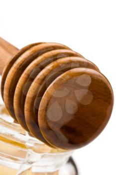 honey in glass jar and wooden stick isolated on white background