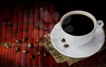 cup of coffee with beans on sack and wood background