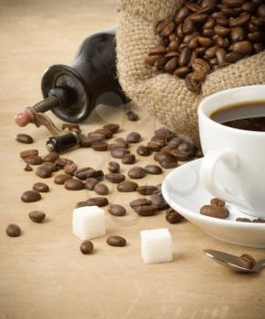 cup of coffee and grinder on wood background