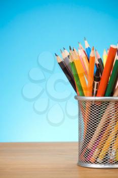 pen and pens in holder on blue background