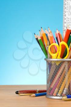 pen and pens in holder on blue background