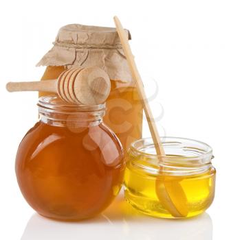 glass pot full of honey, spoon and stick isolated on white background