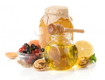 glass jar full of honey, lemon and berry isolated on white background