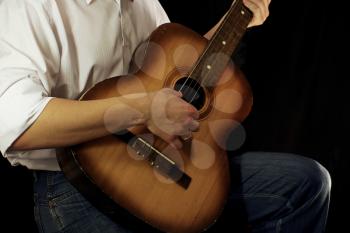 man and guitar at black background