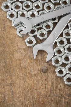metal nuts and wrench tool on wood background texture