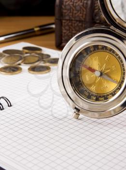 compass, gold coin and pen on checked notebook