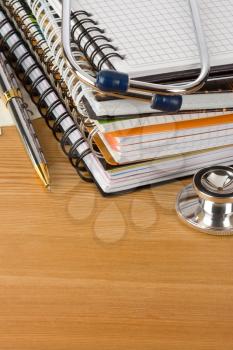 medical stethoscope with notebook on wood  background