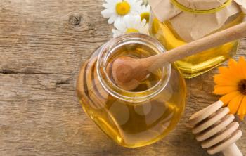 jar of honey and flowers on wood background