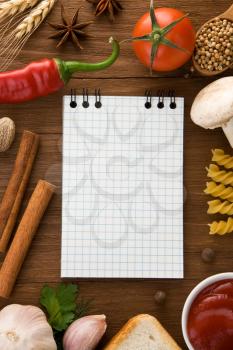 notebook for cooking recipes and spices on wooden table