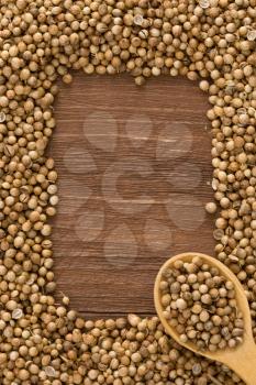coriander spices and spoon on wood background