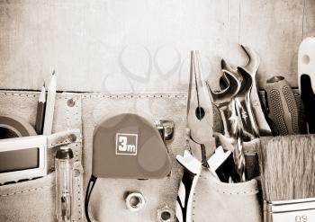 tools in construction belt on wooden background texture