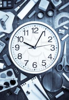 school supplies and clock on wooden background
