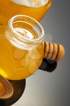 glass jar full of honey and stick on black background