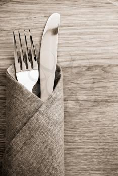 knife and fork at napkin on wooden background