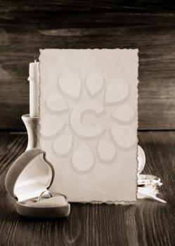 wedding ring and aged paper on wooden background