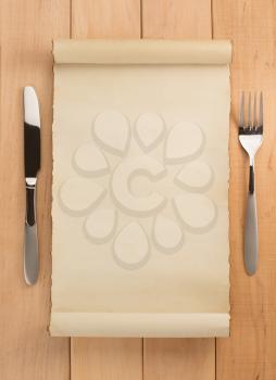 parchment and fork with knife on wooden background