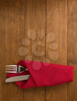 knife and fork at napkin on wooden background