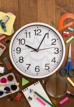 school supplies and clock on wooden background
