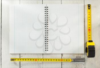 tape measure and notebook on wooden texture