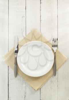 knife and fork with plate at napkin on wooden background