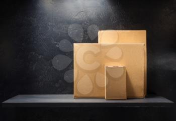 cardboard box on wooden shelf at black background surface