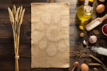 ears of wheat and bakery ingredients on wooden background