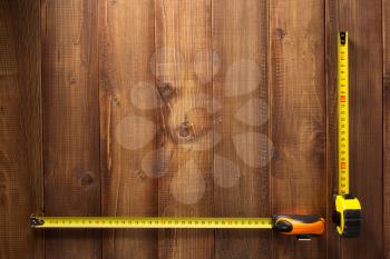 tape measure tools on wooden plank background