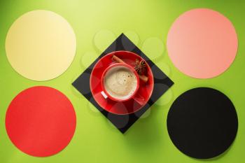 cup of coffee and cinnamon at colorful background