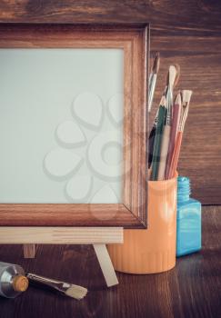 picture frame and paints on wooden background