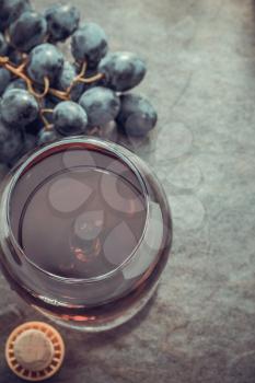 cognac glass and grapes at stone table surface