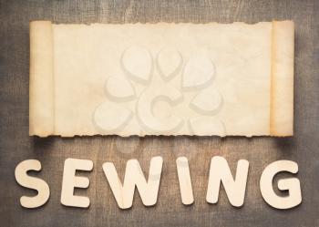 sewing letters and parchment scroll on wooden table background