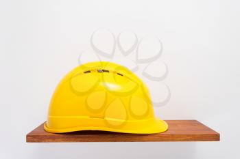 construction helmet on wooden shelf at white background texture wall