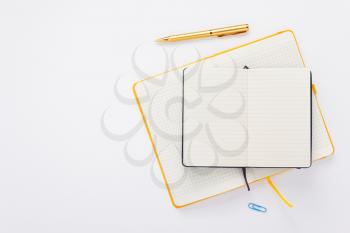 notebook and pen at white paper background, top view