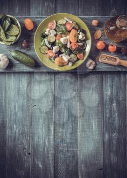 fresh greek salad in plate and ingredients on wooden table