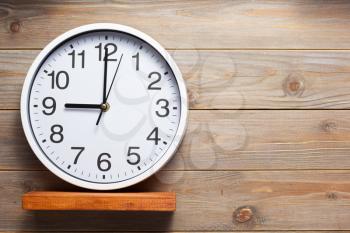 wall clock at wooden shelf on wall background texture