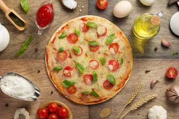 pizza and food ingredients at wooden table, top view